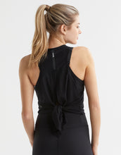 Woman wearing a black sleeveless top with a tie detail on a white background