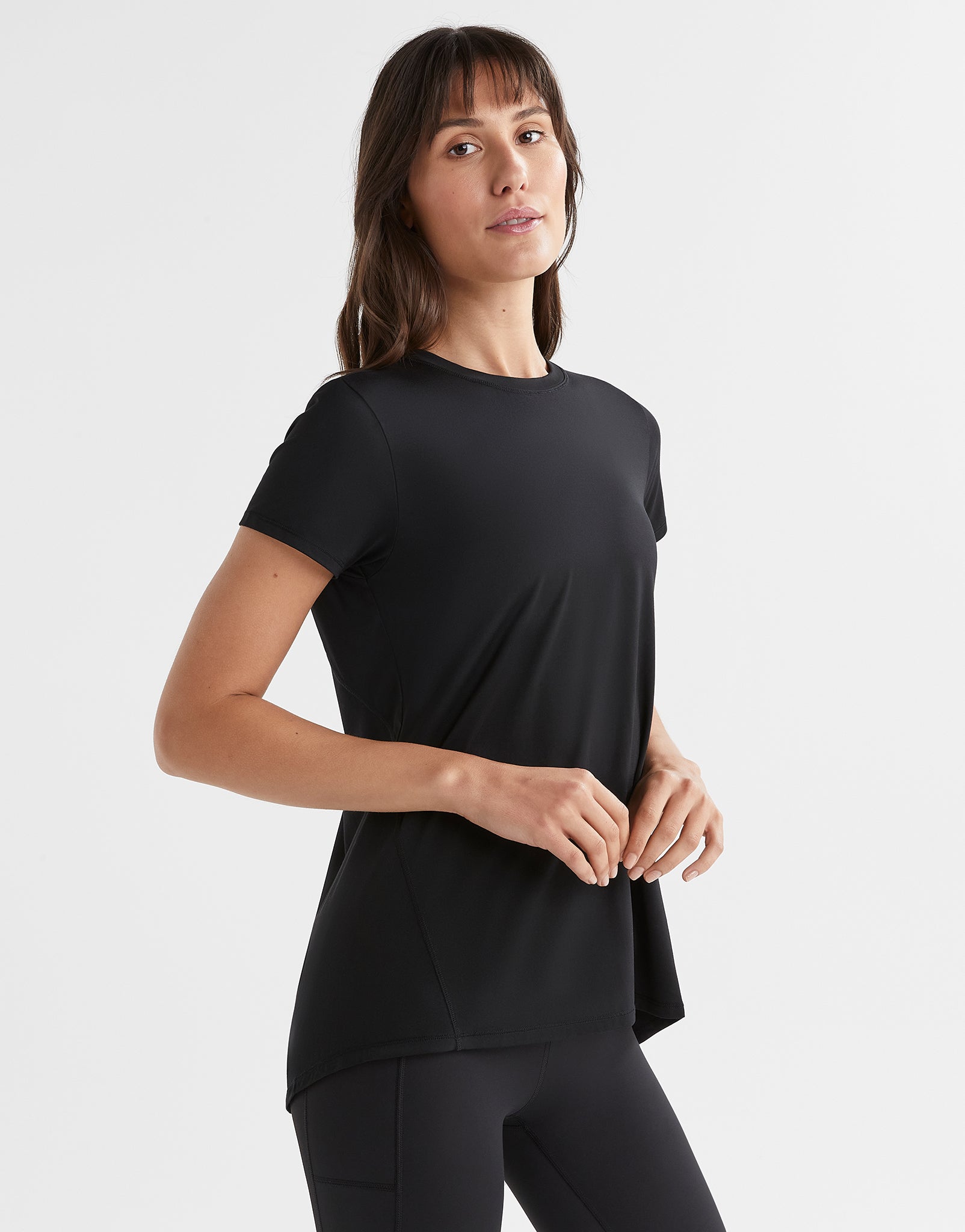 Woman wearing a black short-sleeve top and black leggings on a white background