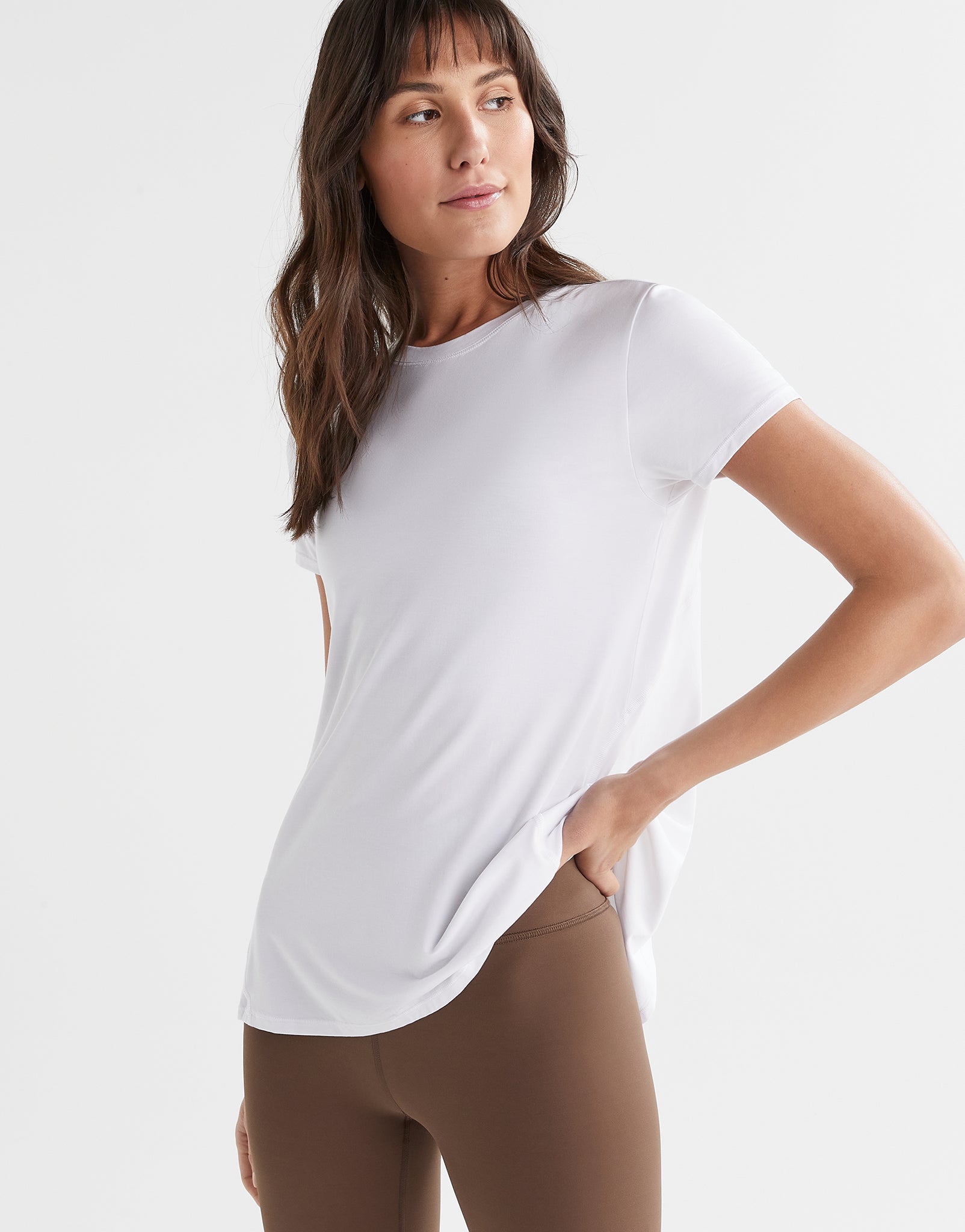 Woman wearing a white t-shirt and brown pants on a plain background