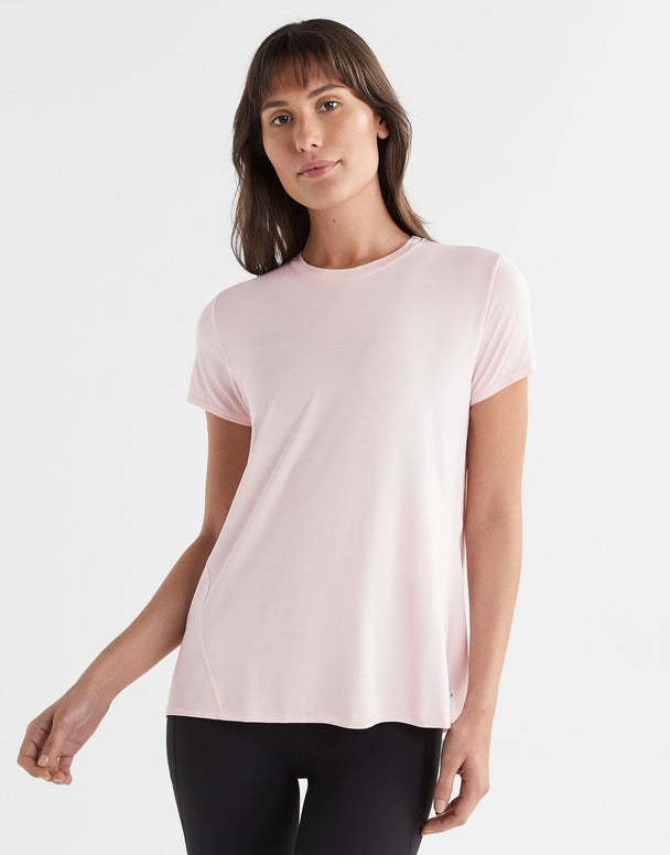 A woman wearing a pink tie-up workout tee with short sleeves.