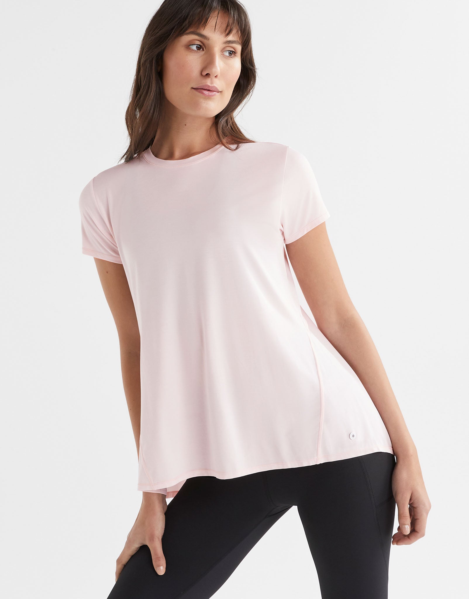 A woman wearing a pink loose top and leggings.