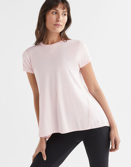 A woman wearing a pink loose top and leggings.