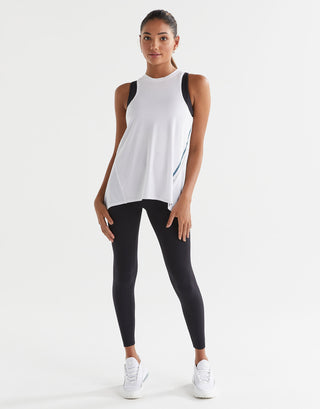 Woman wearing a white sleeveless top and black leggings on a white background