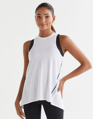 Woman wearing a white sleeveless top with black accents on a light gray background