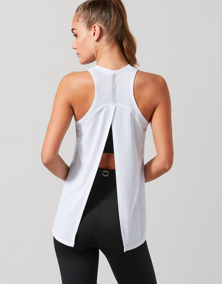 Woman wearing a white sleeveless top and black leggings on a light gray background