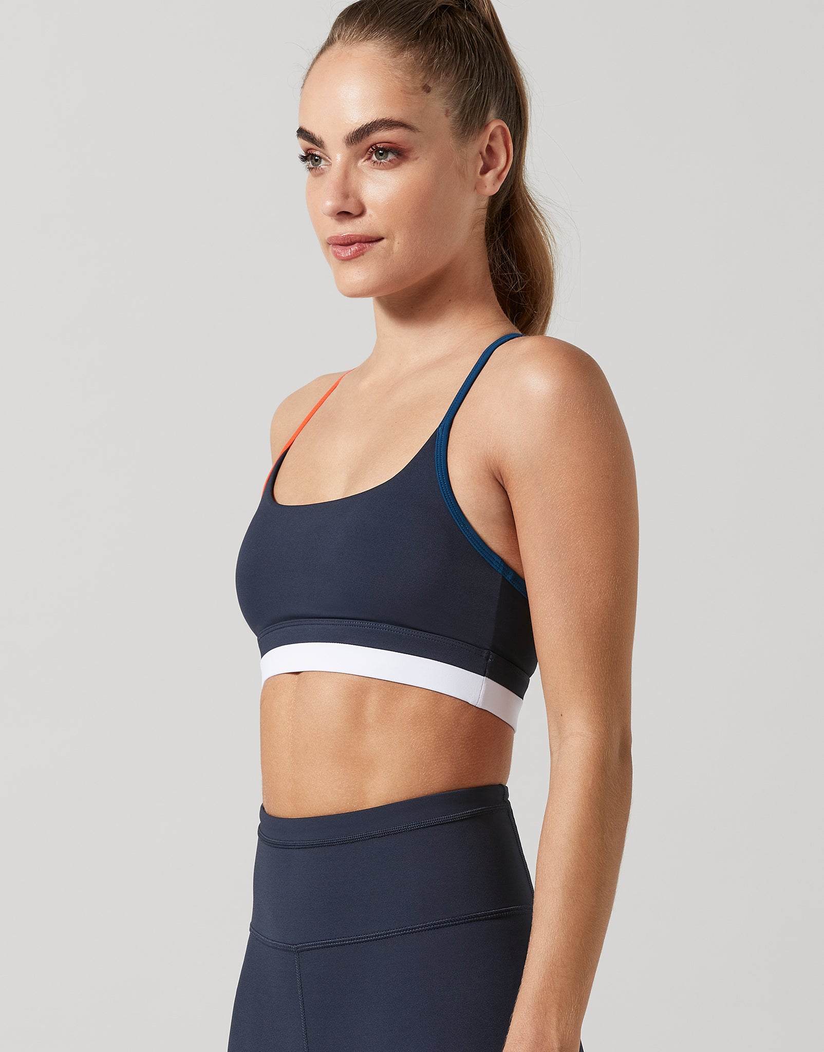 Woman wearing a navy sports bra and leggings on a light gray background