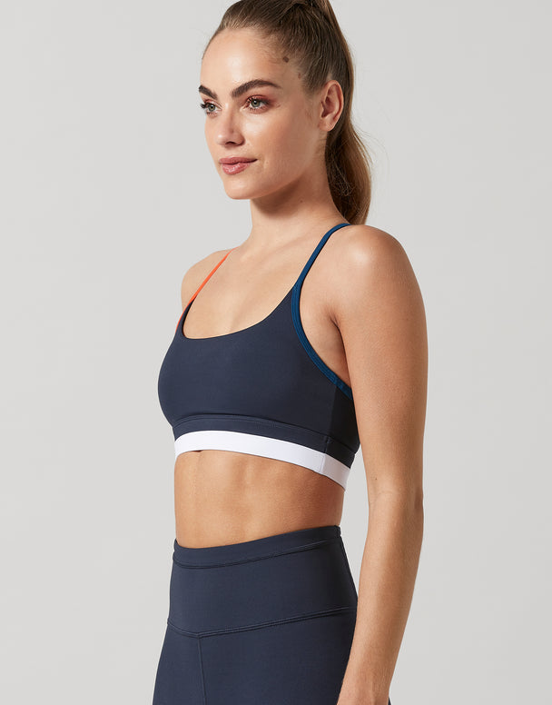 Woman wearing a navy sports bra and leggings on a light gray background