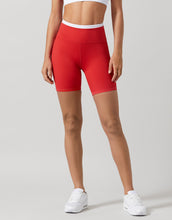 Person wearing red high-waisted shorts on a gray background