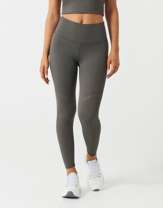 A woman wearing grey leggings and white shoes on a white backround.