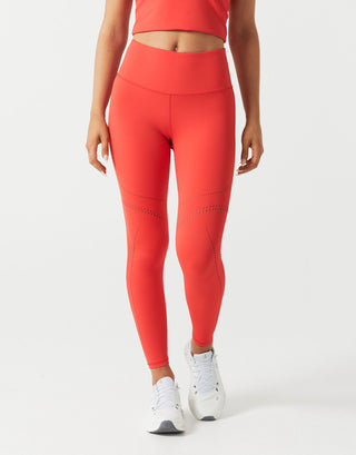 A woman wearing red leggings and a top on a white background.