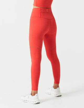 A woman wearing red leggings and a top and white shoes on a white background.