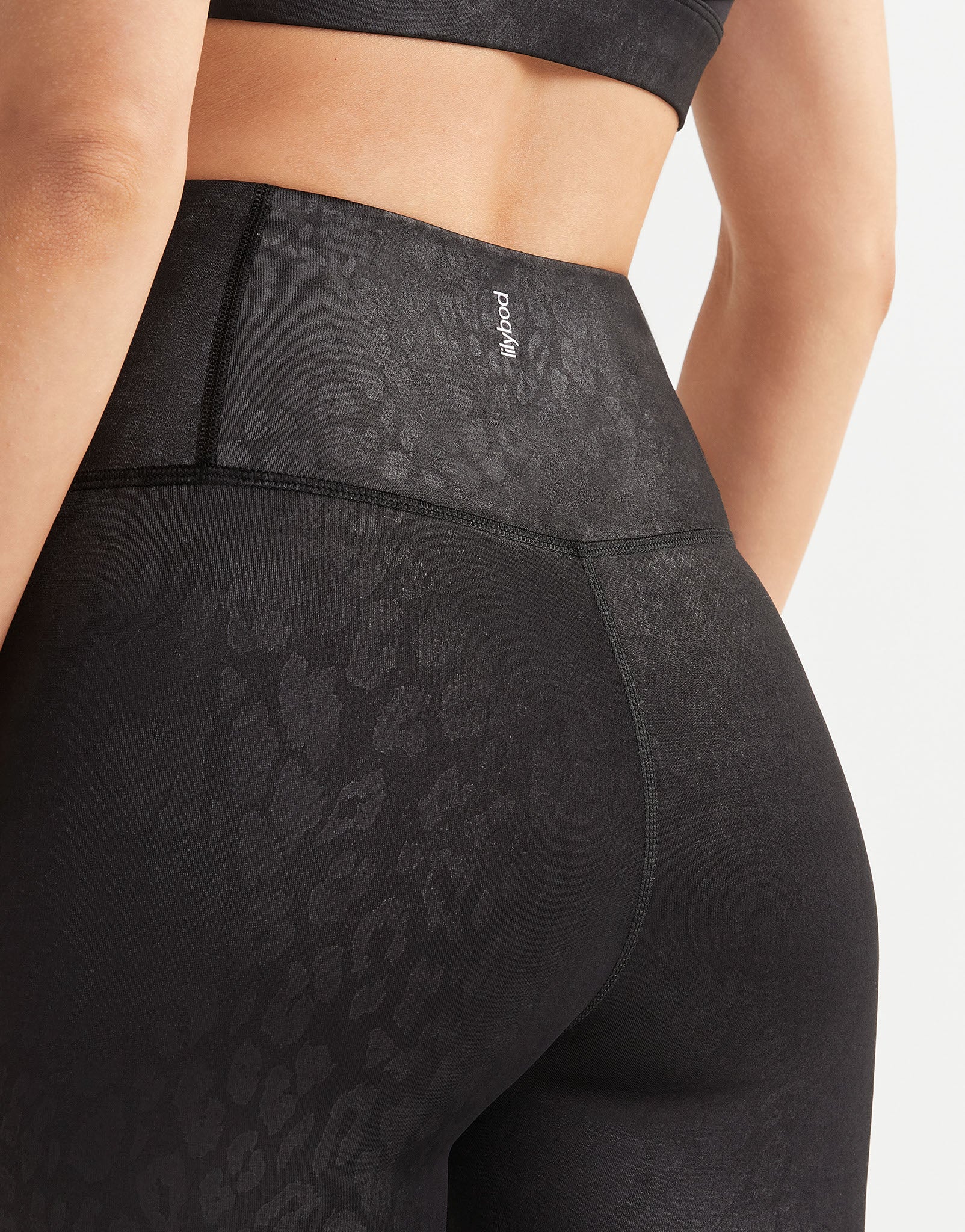 Black leggings with leopard print details on a neutral background