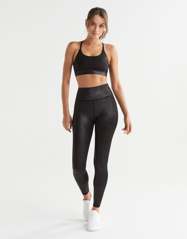 Woman wearing black athletic top and leggings on a white background