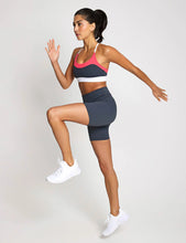 Woman in athletic wear posing against a plain background
