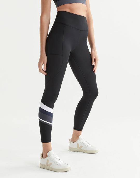 Woman wearing black leggings with a white stripe on a light gray background