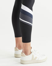 Close up of black leggings with white and grey stripes worn by a person on a white background
