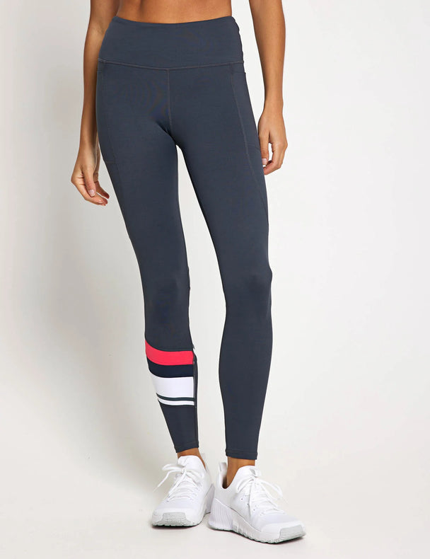 Dark gray leggings with red and white accents worn by a person on a light gray background