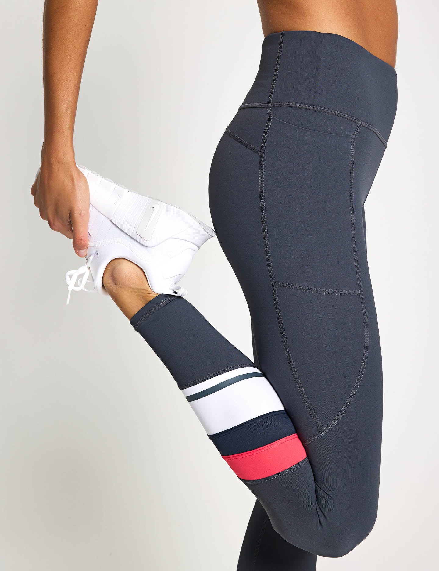 Dark gray leggings with colorful cuffs worn by a person on a light gray background