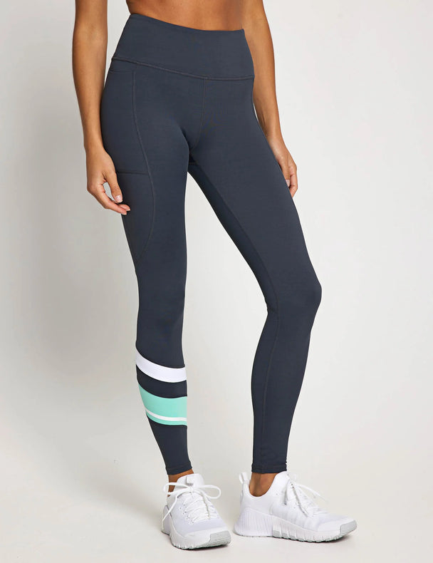 Person wearing dark gray leggings with a colorful stripe on a white background