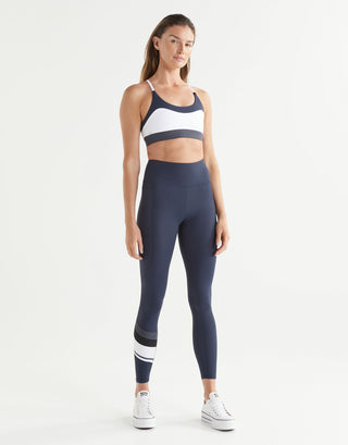 Woman wearing a navy athletic outfit with white accents on a white background