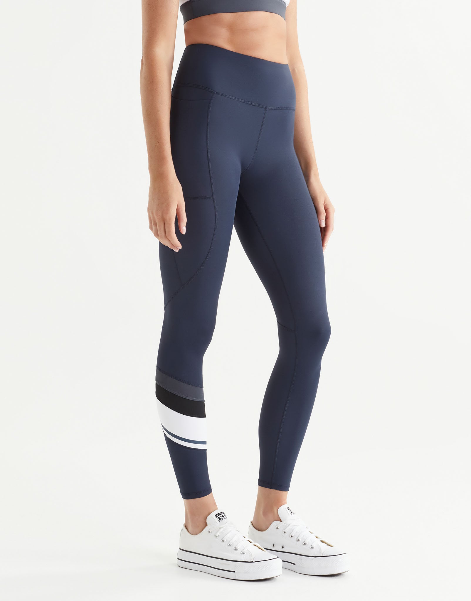 Woman wearing navy leggings with white and black accents on a white background