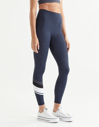Woman wearing navy leggings with white and black accents on a white background