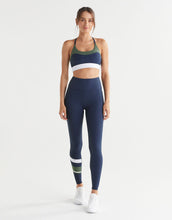 Woman wearing a navy sports bra and leggings with colour blocking on a white background