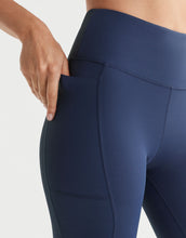 Navy blue leggings with a focus on the waistband and pocket area against a light background.
