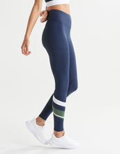 Navy leggings with green and white stripes worn by a woman on a white background