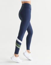 Navy leggings with white and green stripes worn by a woman on a light grey background
