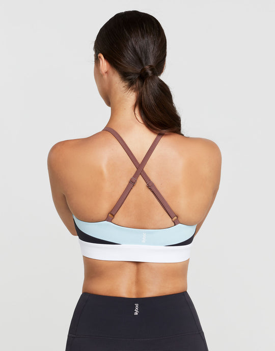 A woman wearing a sports bra with color blocked accent stripes in charcoal and pale blue.