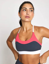 Woman wearing a colorful sports bra against a plain background
