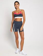 Woman wearing a sports bra and shorts on a plain background
