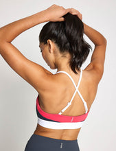Person wearing a sports bra with criss-cross straps on a plain background