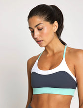 Woman wearing a sports bra with a gray and white design on a plain background