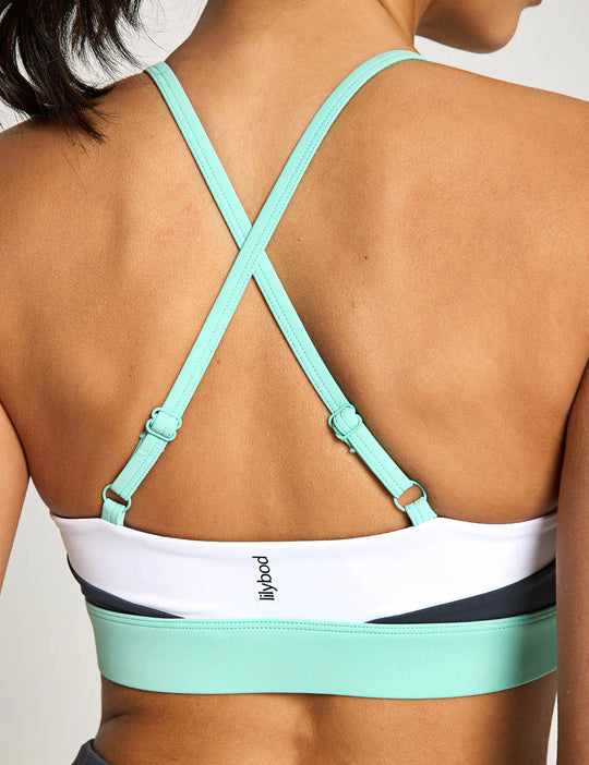 Mint green sports bra with criss-cross straps on a neutral background