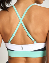 Mint green sports bra with criss-cross straps on a neutral background