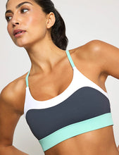 Woman wearing a sports bra with a white and navy design on a plain background