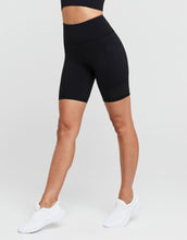 Person wearing black high-waisted shorts on a white background