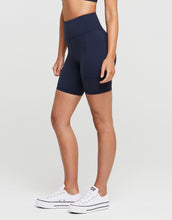 Woman wearing navy blue athletic shorts on a light gray background