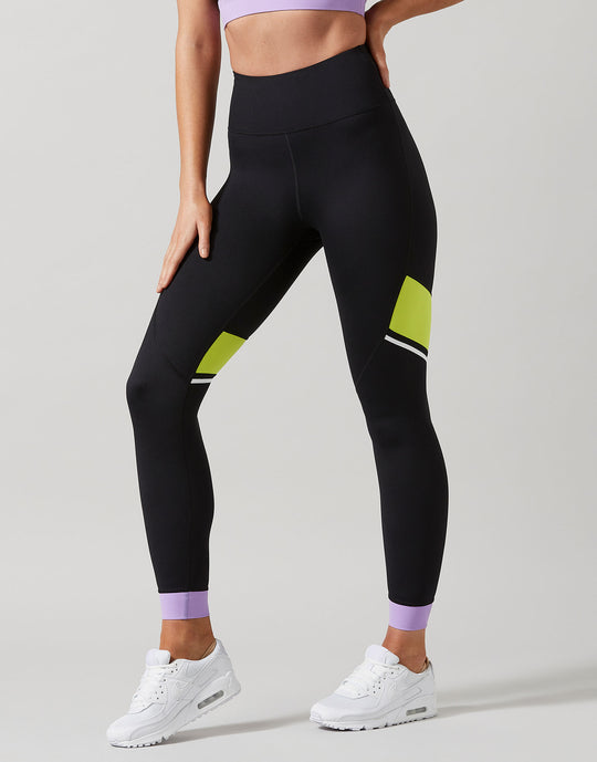 Person wearing black leggings with green and white accents on a plain background