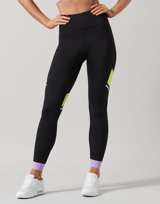 Person wearing black leggings with purple accents on a gray background