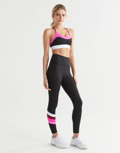 Woman wearing a black and pink sports bra and leggings set on a white background