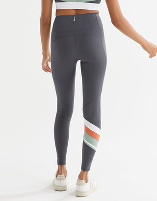 Gray leggings with colorful stripes worn by a person on a white background