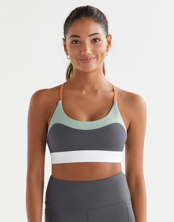 Woman wearing a sports bra and leggings on a plain background