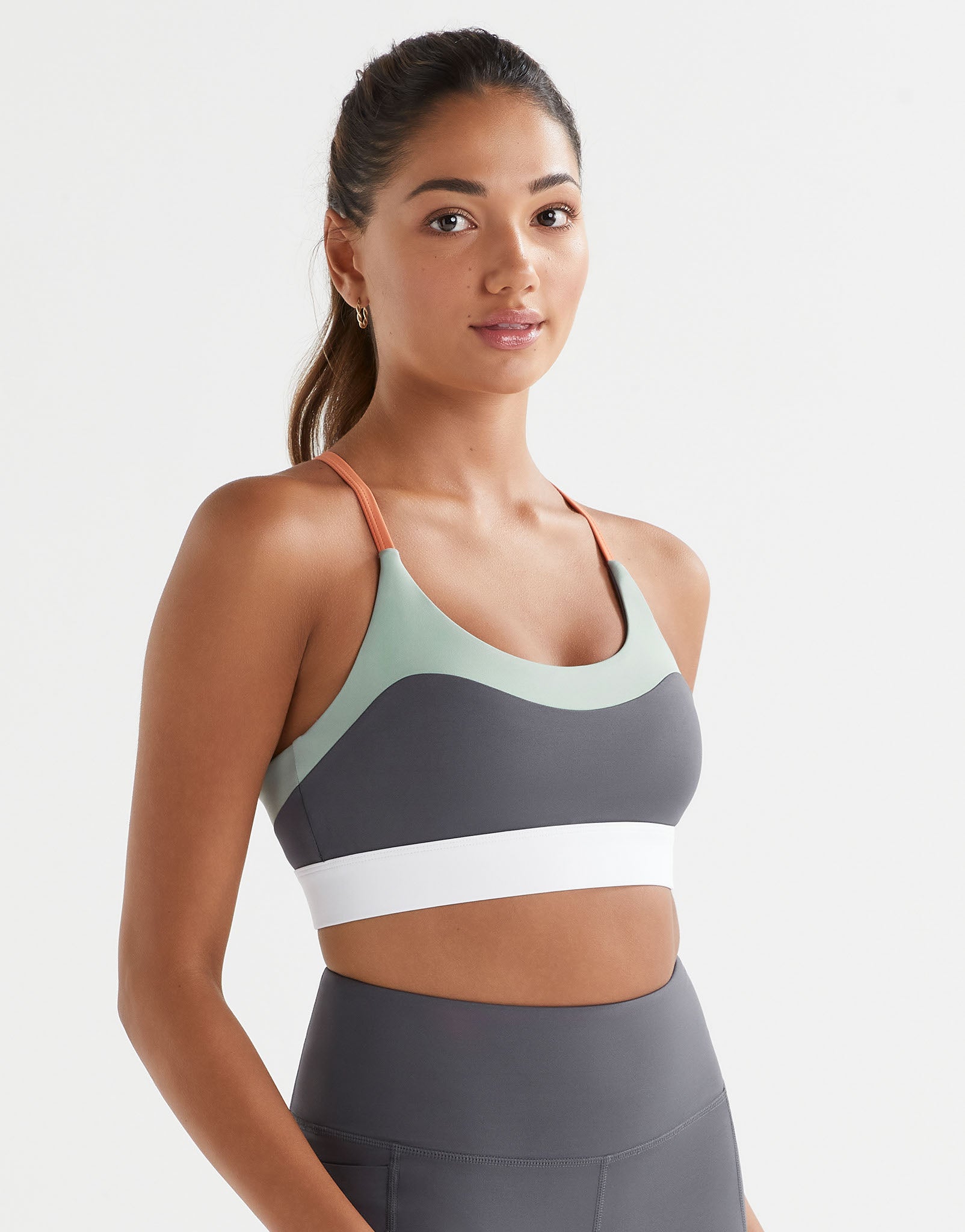 Woman wearing a sports bra and leggings on a plain background