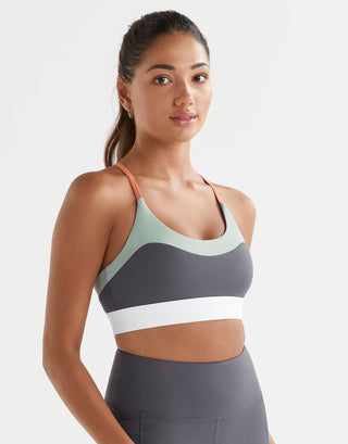 Woman wearing a sports bra and leggings on a plain background