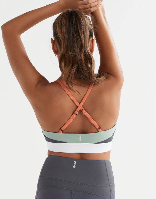 Woman wearing a sports bra and leggings with a plain background