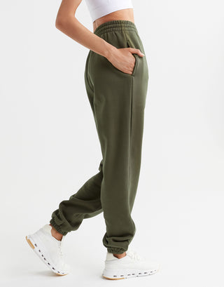 A woman wearing a pair of Lilybod olive green sweatpants and white runners.