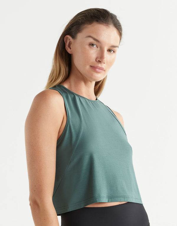 Woman wearing a green sleeveless top against a white background